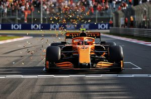 Un monoplaza naranja de Fórmula 1 cruzando la recta de línea de meta en un circuito.